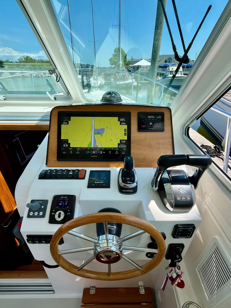 Slide: The Image of 2023 Back Cove 34O helm with navigation display and controls, docked at marina. - 19