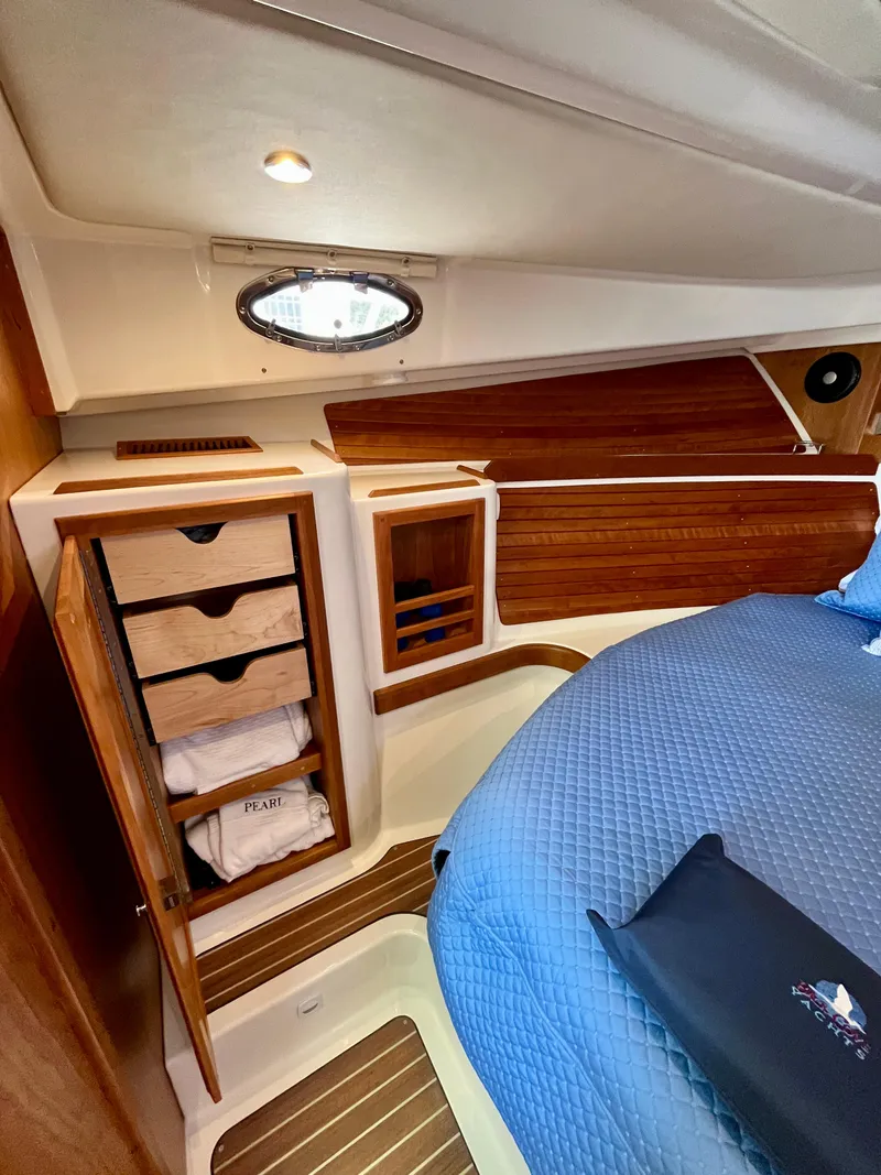 Slide: The Image of 2023 Back Cove 34O cabin interior with wooden storage and blue bedding. - 23