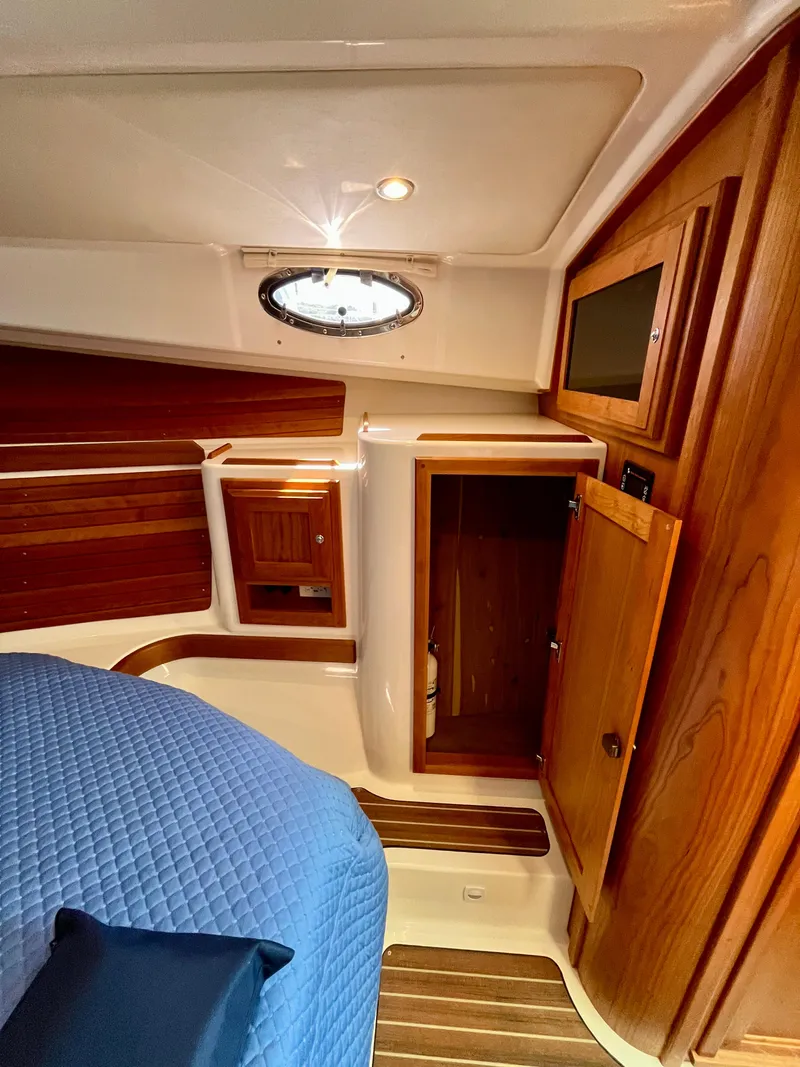 Slide: The Image of 2023 Back Cove 34O cabin interior with wood finish and blue bedding. - 24