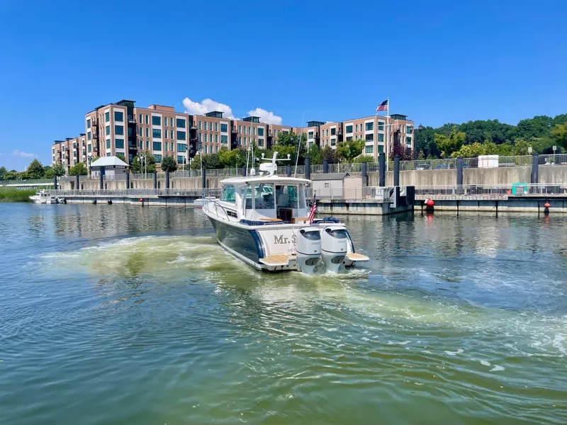 Slide: The Image of 2023 Back Cove 34O boat cruising near modern waterfront buildings. - 40