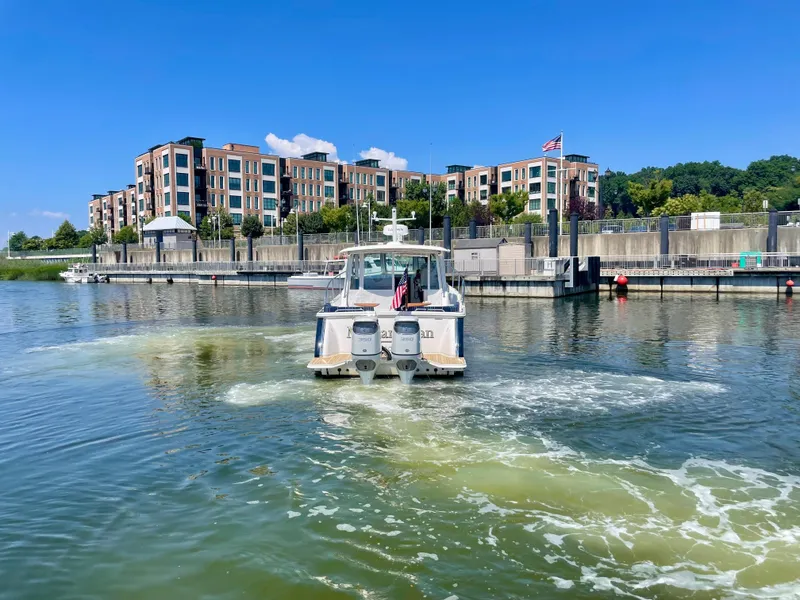 Slide: The Image of 2023 Back Cove 34O boat cruising in a marina with modern buildings in the background. - 41