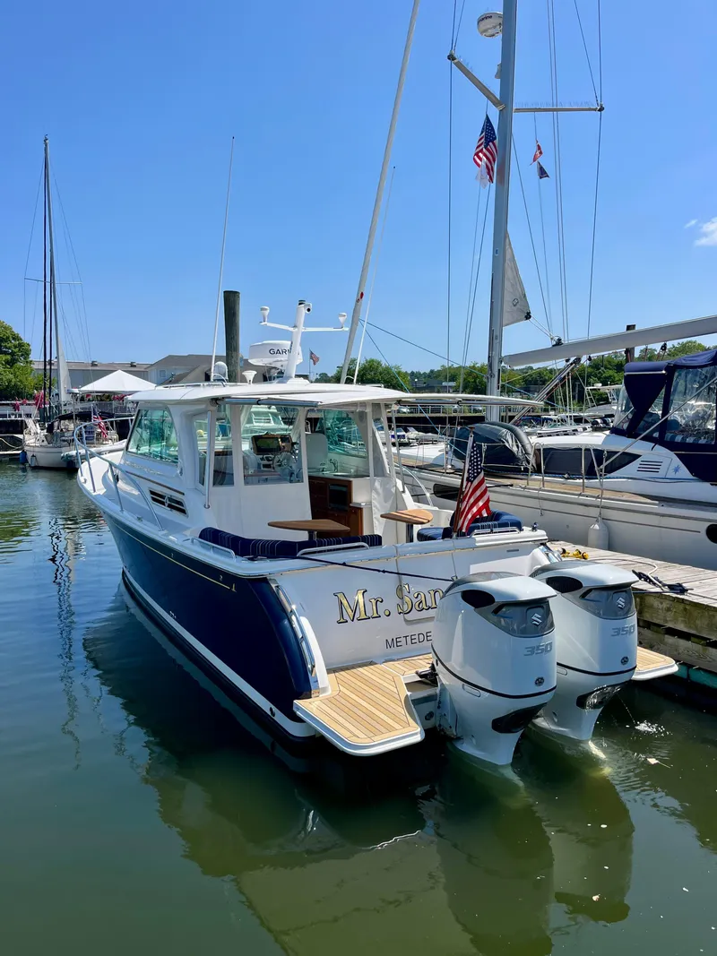 Slide: The Image of 2023 Back Cove 34O boat docked, featuring dual outboard engines and American flag. - 5