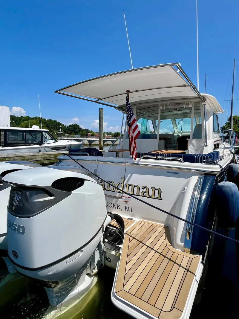 Slide: The Image of 2023 Back Cove 34O yacht docked, featuring outboard motor and American flag. - 7
