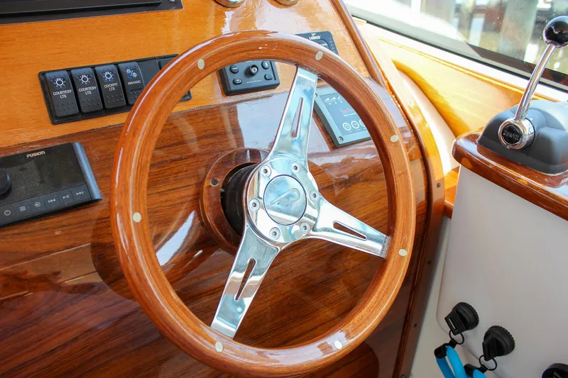 Slide: The Image of Steering wheel of a 2008 Hinckley Talaria 38R Convertible yacht, featuring polished wood and metal accents. - 18