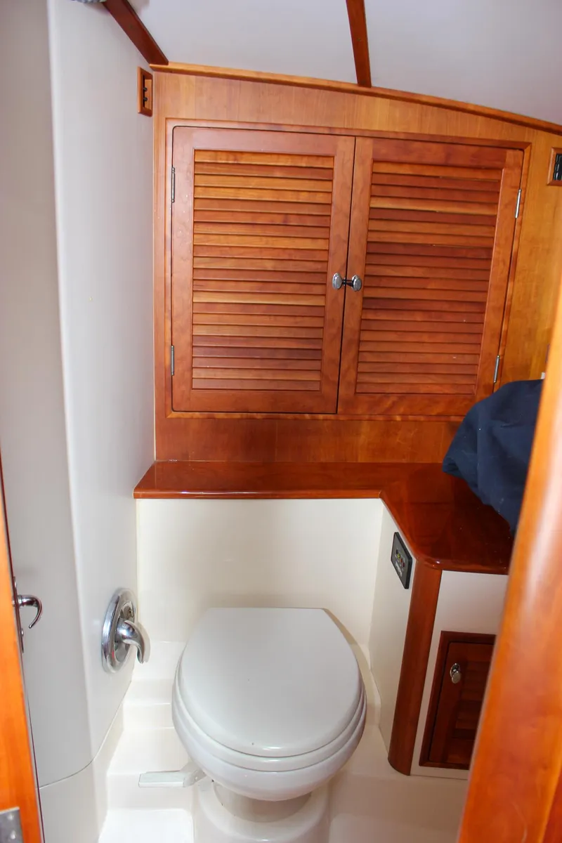 Slide: The Image of 2008 Hinckley Talaria 38R Convertible yacht bathroom with wooden cabinets and white toilet. - 34