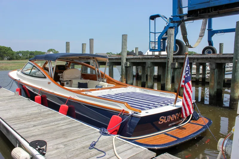 Slide: The Image of 2008 Hinckley Talaria 38R Convertible docked with American flag and wooden deck. - 44