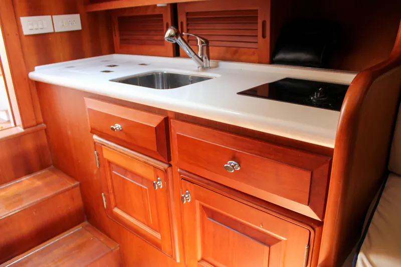 Slide: The Image of 2008 Hinckley Talaria 38R Convertible yacht interior with wooden cabinetry and compact kitchen area. - 29