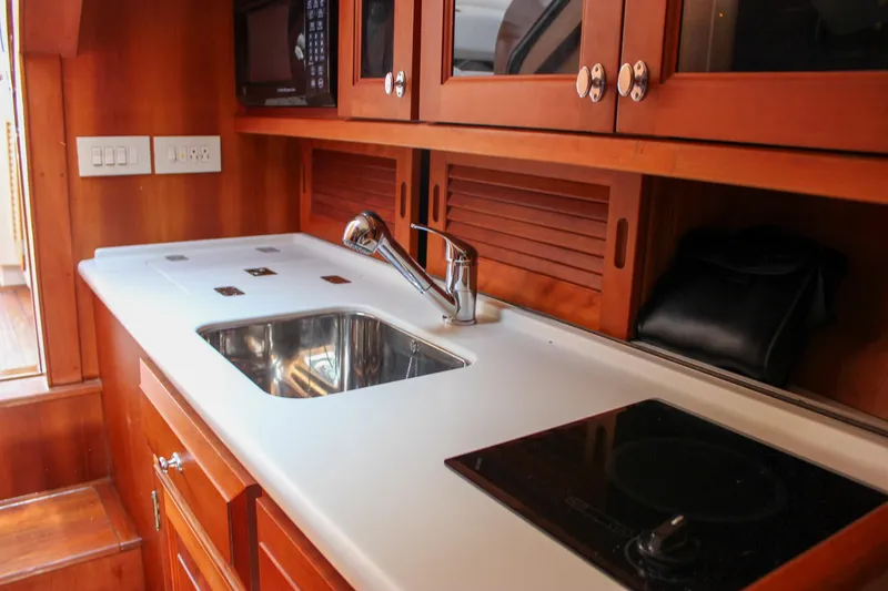 Slide: The Image of 2008 Hinckley Talaria 38R Convertible yacht kitchen with sink, stove, and wooden cabinetry. - 31