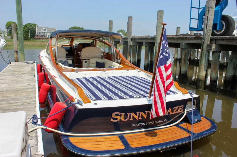 Slide: The Image of 2008 Hinckley Talaria 38R Convertible docked, displaying American flag and striped seating. - 45