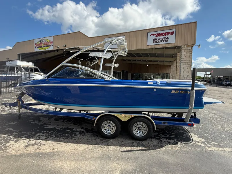 Slide: The Image of 2008 Supra Launch 22 SSV boat in blue, parked outside a dealership under a clear sky. - 2