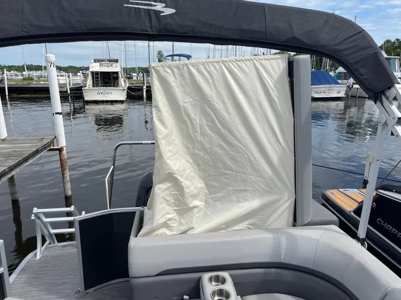 Slide: The Image of 2022 Bennington 21 SX pontoon boat with canopy and privacy curtain at marina. - 21