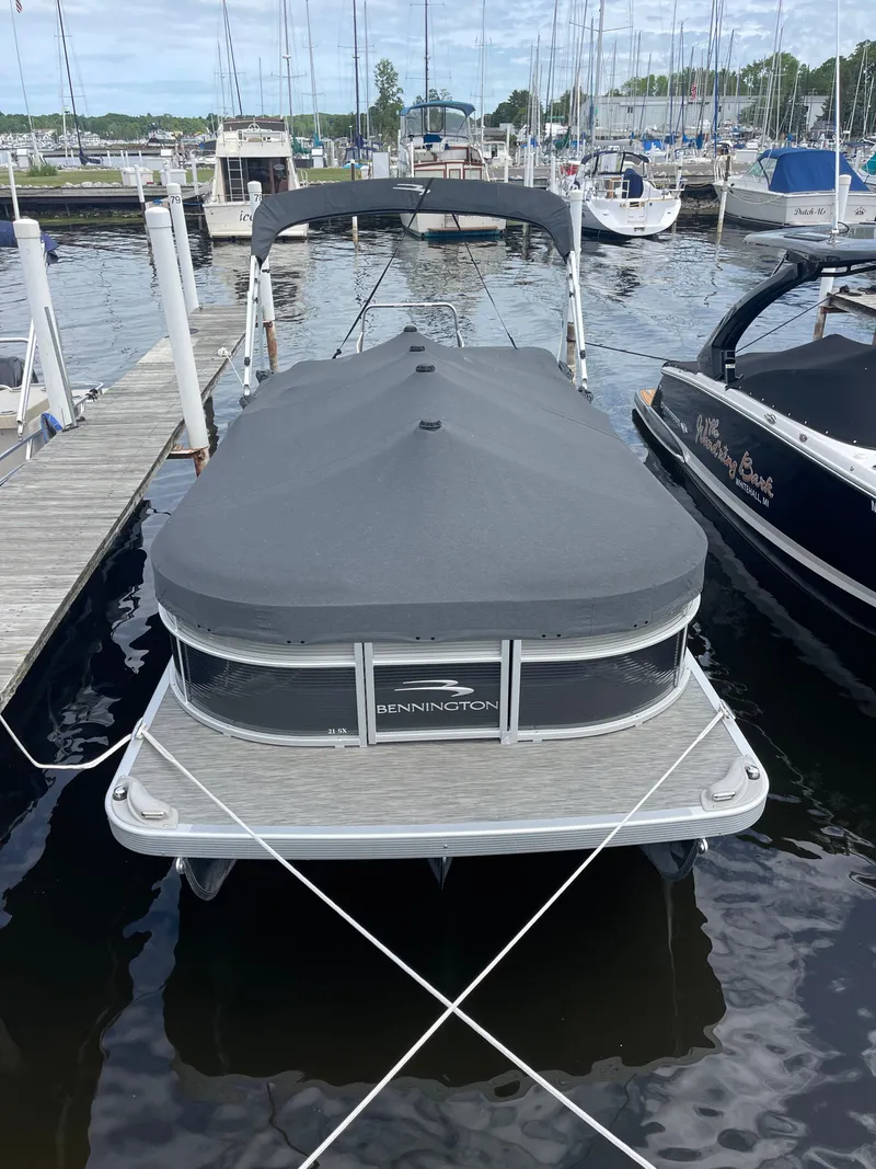 Slide: The Image of 2022 Bennington 21 SX pontoon boat docked with cover, surrounded by other boats. - 3