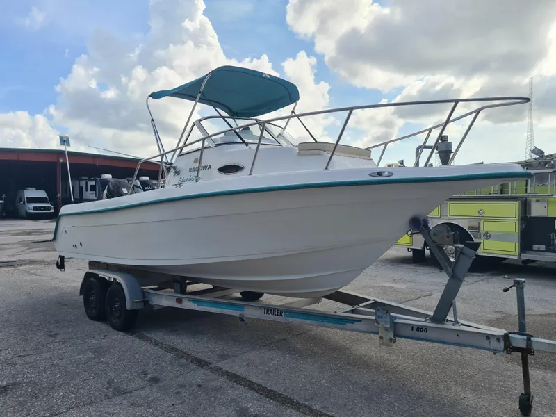 Slide: The Image of 2000 Key West 2300 WA Bluewater boat on trailer, parked outdoors under cloudy sky. - 4
