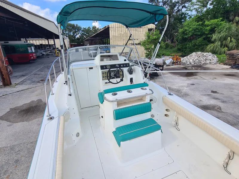 Slide: The Image of 2000 Key West 2300 WA Bluewater boat with teal seating and canopy, docked outdoors. - 8