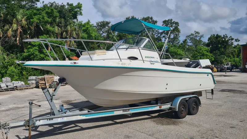 The Image of 2000 Key West 2300 WA Bluewater boat on trailer, parked outdoors with lush greenery background. - 0