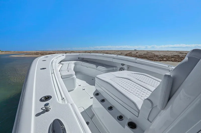 Slide: The Image of 2026 Yellowfin 36 Offshore boat interior with luxurious seating, near a sandy shore under clear blue skies. - 31