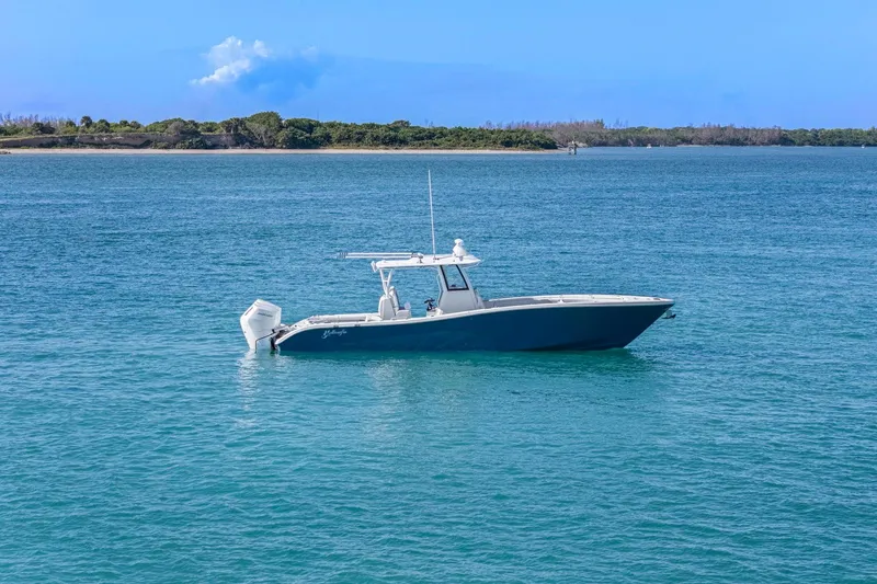 Slide: The Image of 2026 Yellowfin 36 Offshore boat on calm blue water near a scenic shoreline. - 52