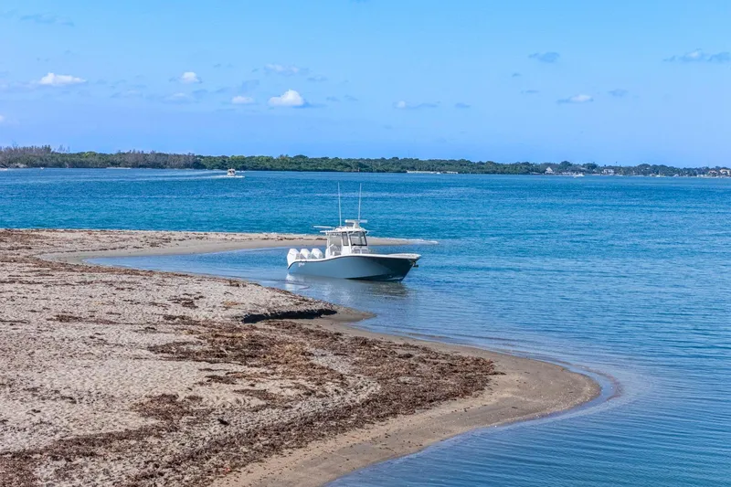 Slide: The Image of 2026 Yellowfin 36 Offshore boat anchored on a sandy beach with clear blue water. - 64