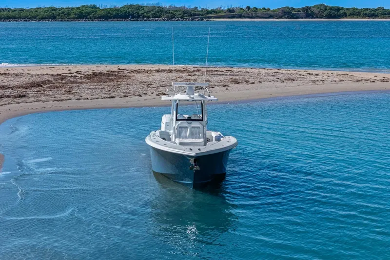 Slide: The Image of 2026 Yellowfin 36 Offshore boat anchored near a sandy beach with clear blue water. - 67