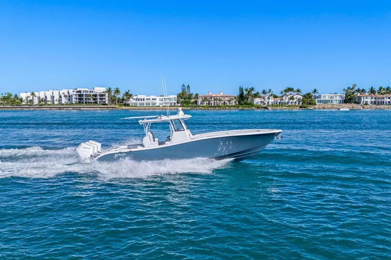 Slide: The Image of 2026 Yellowfin 36 Offshore boat cruising on clear blue water near a coastal cityscape. - 7