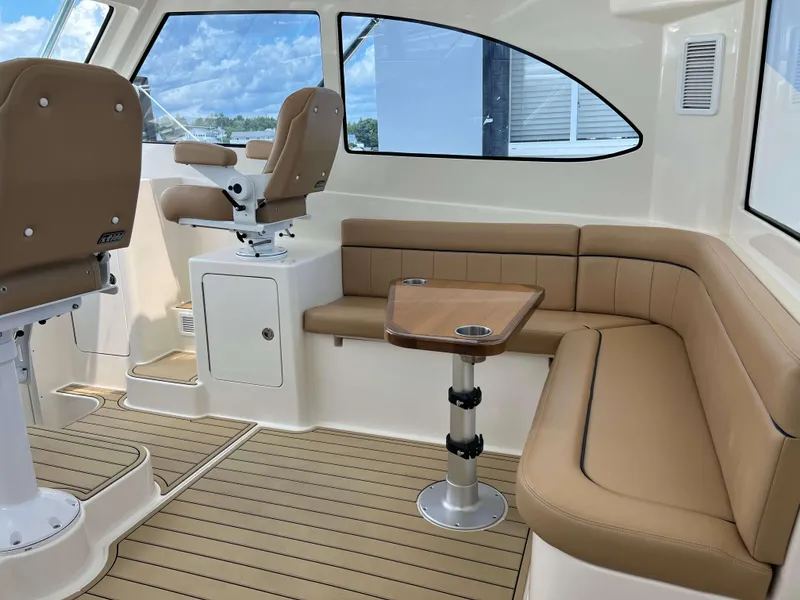 Slide: The Image of Interior of 2022 Henriques 42 Express Hardtop with tan seating and wooden table. - 44
