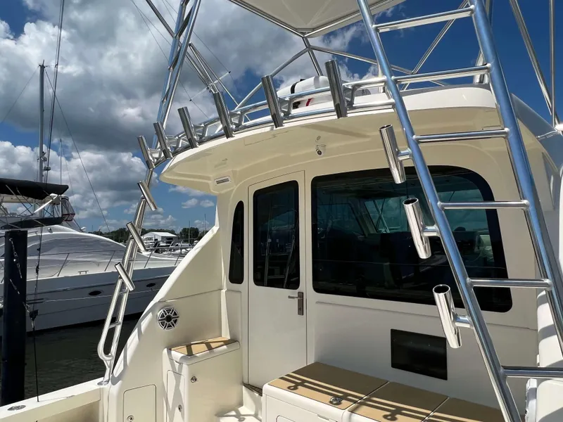 Slide: The Image of 2022 Henriques 42 Express Hardtop boat with ladder and seating, docked under a cloudy sky. - 7