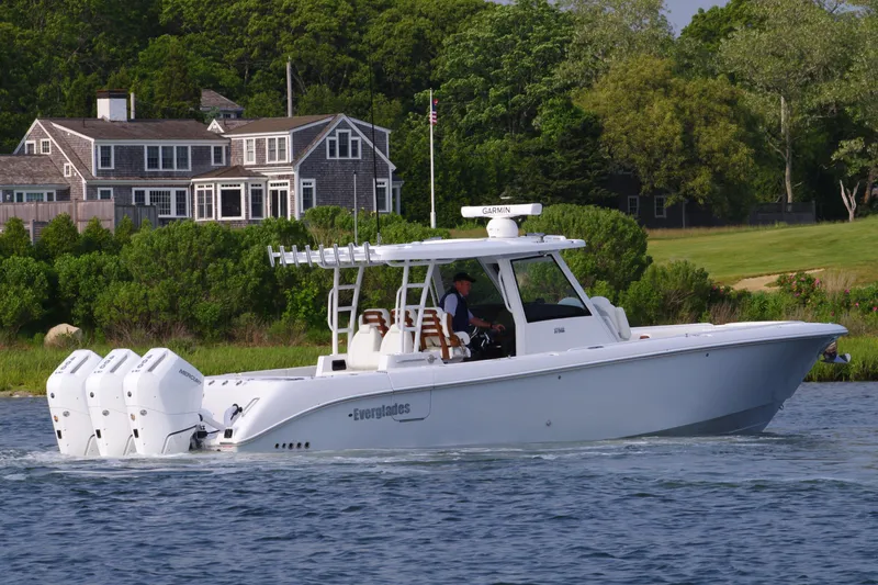 Slide: The Image of 2025 Everglades 375 Center Console boat cruising near a coastal home. - 11