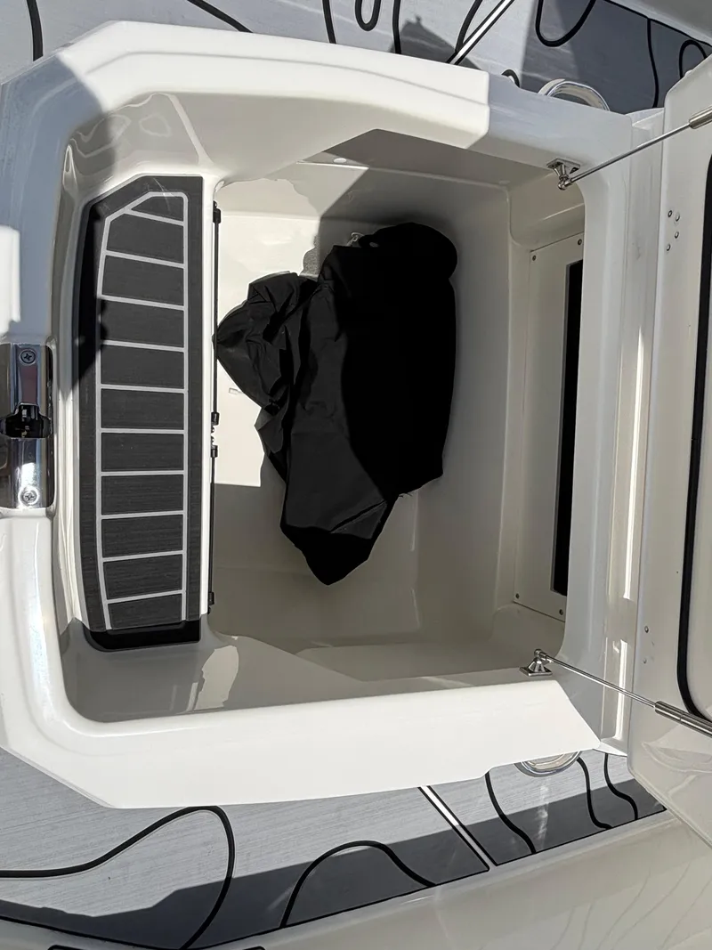 Slide: The Image of Storage compartment of 2023 Boston Whaler 220 Dauntless boat, featuring black fabric inside. - 16
