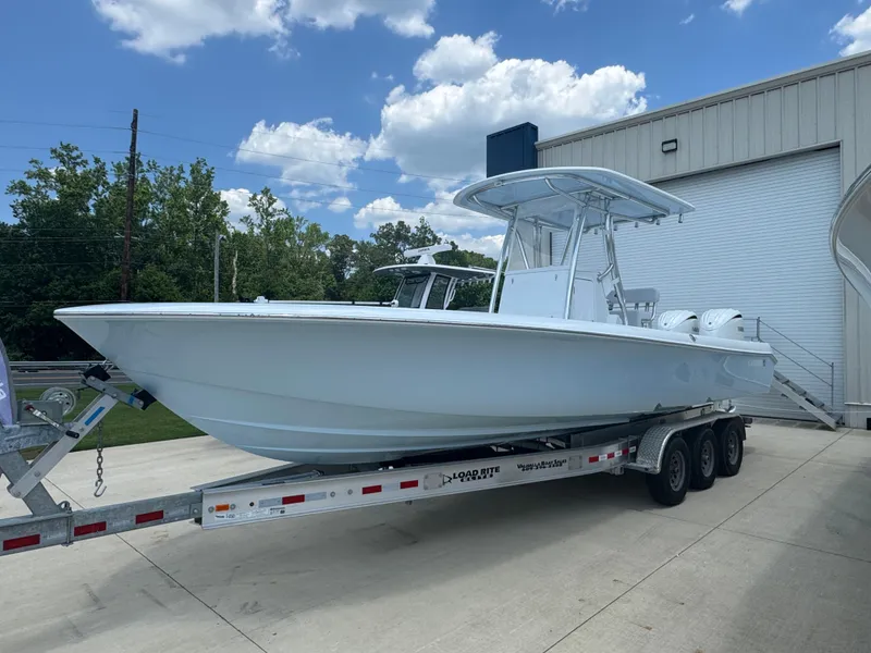 The Image of 2025 Contender 29 Bay boat on trailer, parked outdoors under a partly cloudy sky. - 1