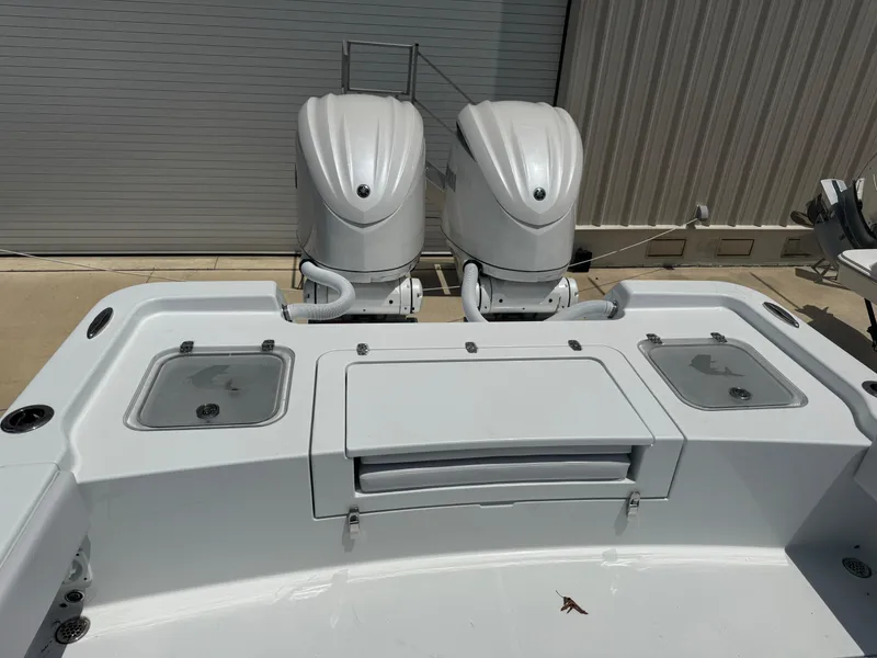 Slide: The Image of 2025 Contender 29 Bay boat with dual outboard engines, docked near a metal building. - 5