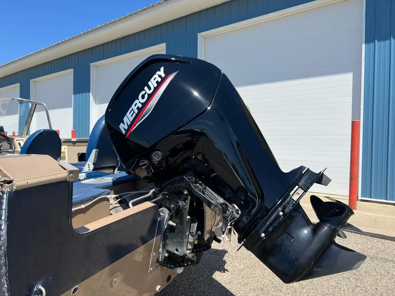 Slide: The Image of 1998 Lund 1700 Pro Sport Adventure boat with Mercury outboard motor, parked near blue building. - 13