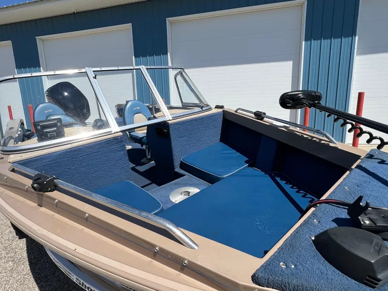 Slide: The Image of 1998 Lund 1700 Pro Sport Adventure boat with blue interior, parked near a blue building. - 5