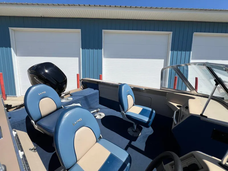 Slide: The Image of 1998 Lund 1700 Pro Sport Adventure boat with blue seats, parked near blue building. - 6