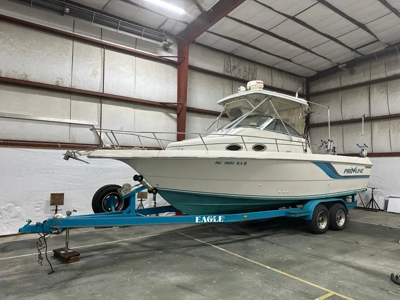 The Image of 1996 Pro-Line 251 Walkaround I/O boat on trailer in indoor storage facility. - 0