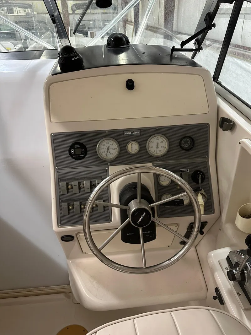 Slide: The Image of 1996 Pro-Line 251 Walkaround I/O boat dashboard with steering wheel and gauges. - 15