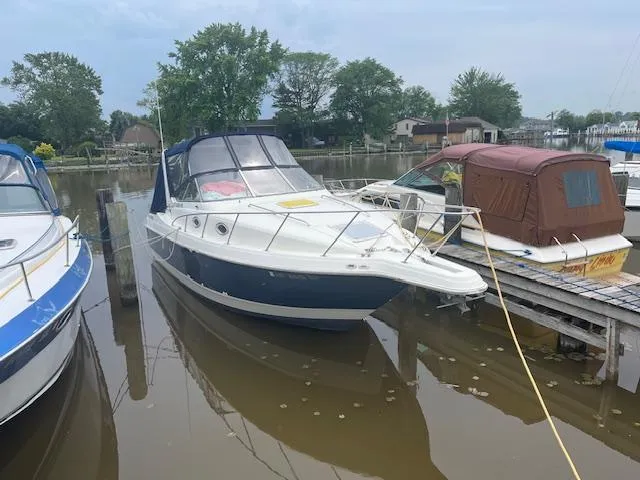 The Image of 1997 Monterey 296 Cruiser docked at a marina, surrounded by calm water and trees. - 1