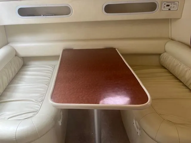 Slide: The Image of Interior of a 1997 Monterey 296 Cruiser with beige seating and a wooden table. - 13