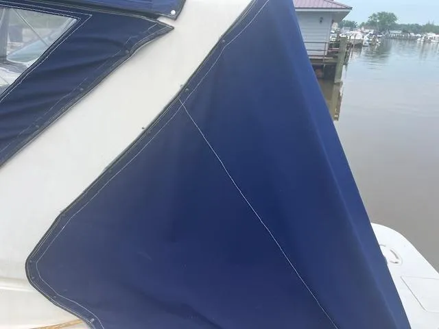 Slide: The Image of 1997 Monterey 296 Cruiser with blue canvas cover docked by the water. - 4