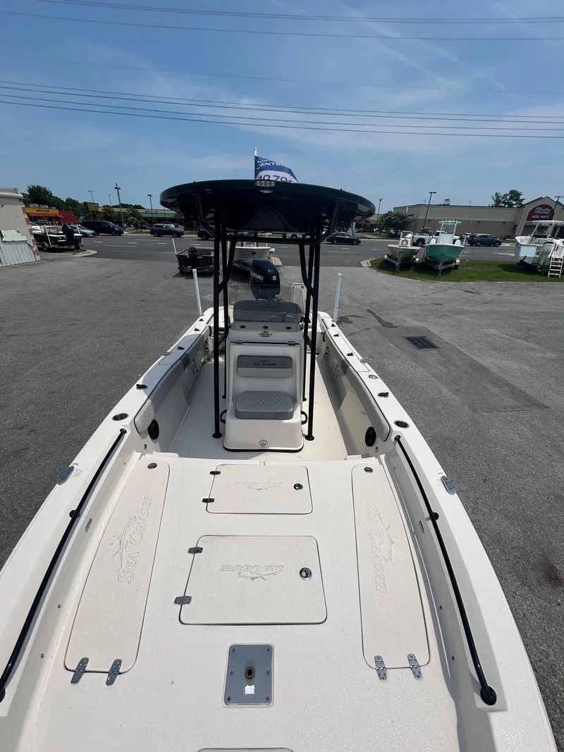 Slide: The Image of 2025 Sea Chaser 26 LX boat with T-top, parked on asphalt, under clear blue sky. - 10
