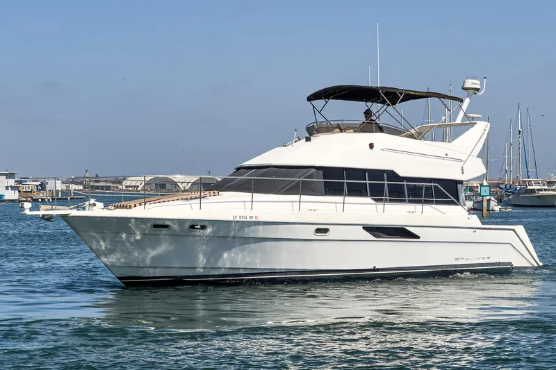 The Image of 1992 Bayliner 4388 yacht cruising in a marina under clear blue skies. - 1