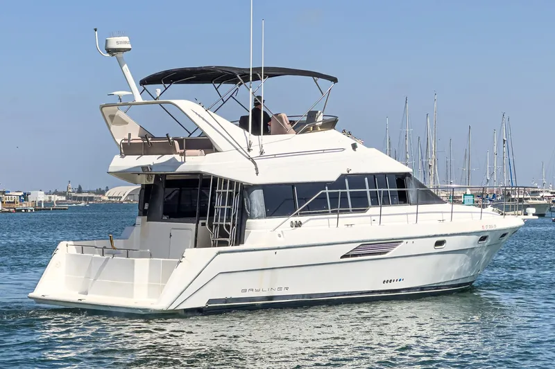 Slide: The Image of 1992 Bayliner 4388 yacht cruising in a marina with clear blue skies. - 6