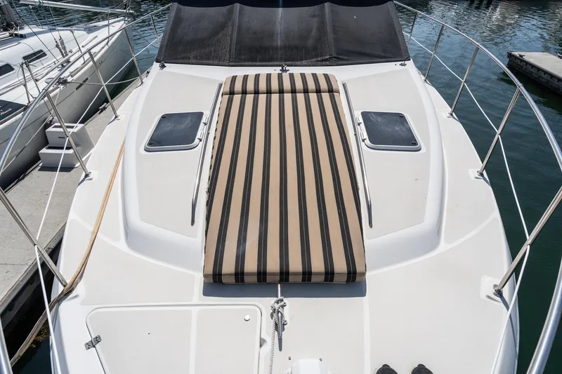 Slide: The Image of 1992 Bayliner 4388 yacht deck with striped sunbed and railing, docked at marina. - 8