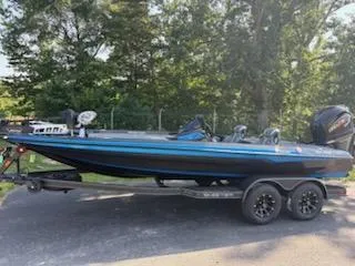 The Image of 2026 Skeeter ZXE20 bass boat on trailer, parked outdoors with trees in background. - 1