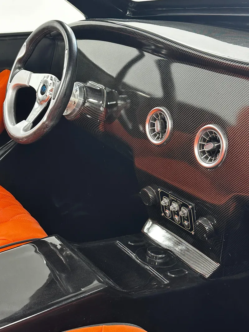 Slide: The Image of Interior of 2025 Fabbro Jet Car RR with carbon fiber dashboard and orange seats. - 25