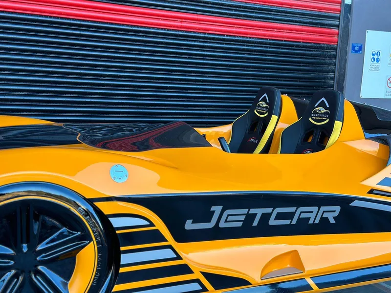 Slide: The Image of 2025 Fabbro Jet Car RR, sleek yellow and black design, parked near a striped garage door. - 47