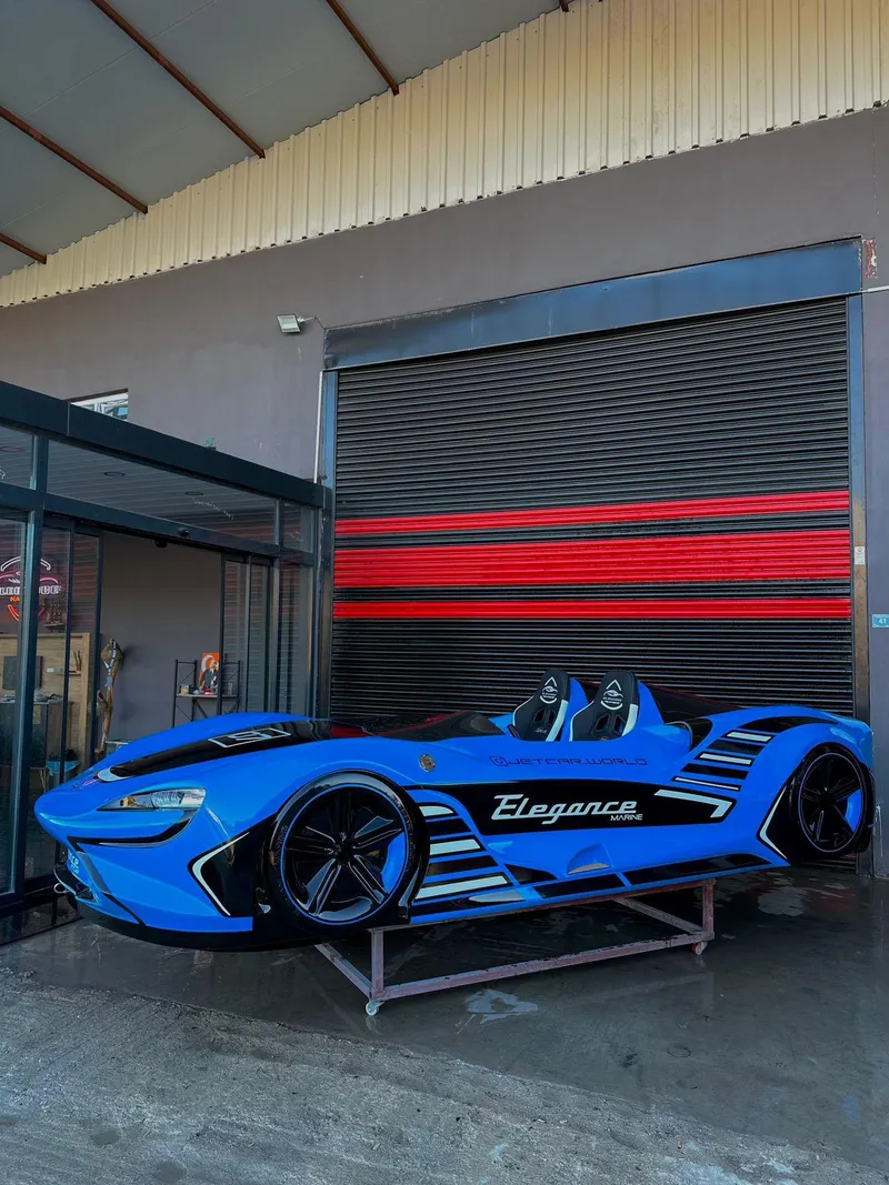 Slide: The Image of Fabbro Jet Car RR 2025 in blue, parked outside a garage with red-striped door. - 48