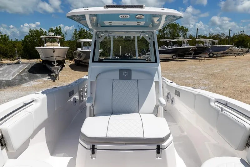 Slide: The Image of 2026 Sea Fox 288 Commander boat interior with white seating and console, parked outdoors. - 22