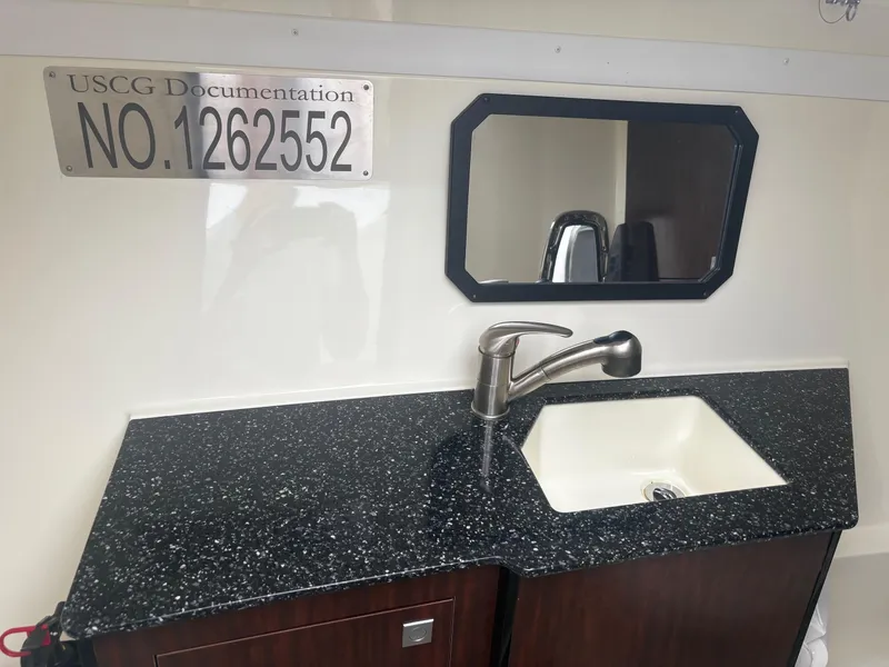 Slide: The Image of 2014 Monterey 328 Super Sport boat interior with sink, mirror, and USCG documentation number. - 17