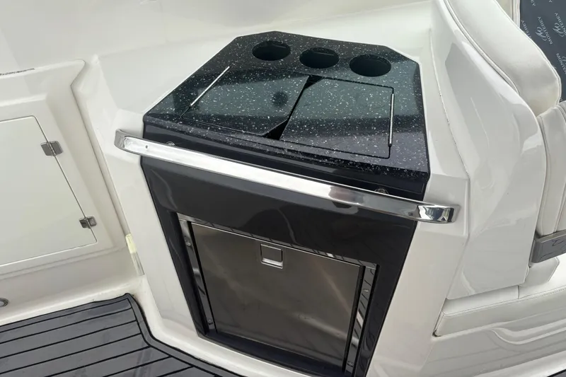 Slide: The Image of 2014 Monterey 328 Super Sport boat interior with sleek black countertop and built-in storage. - 23