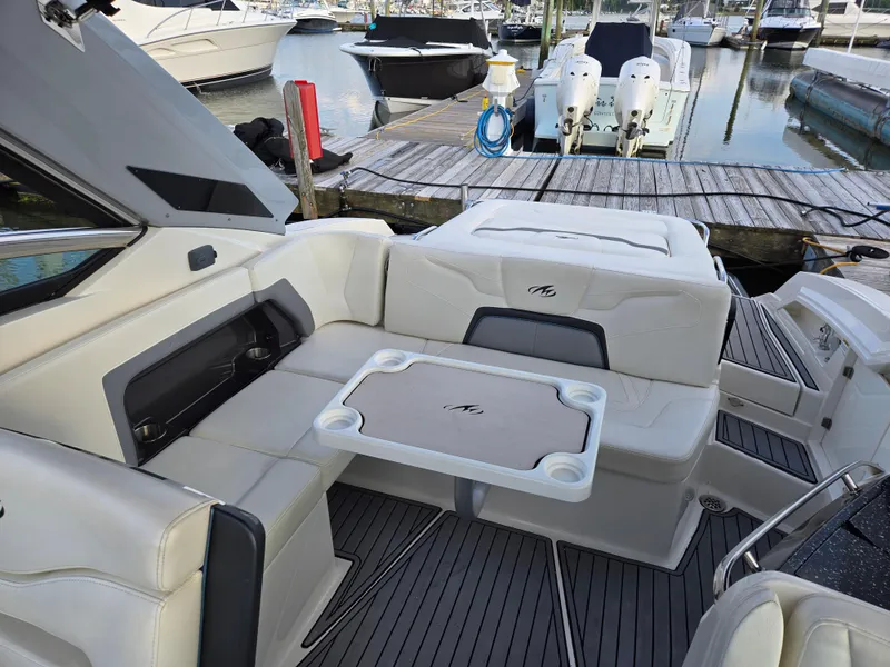 Slide: The Image of 2014 Monterey 328 Super Sport boat interior with seating and table at a marina. - 4
